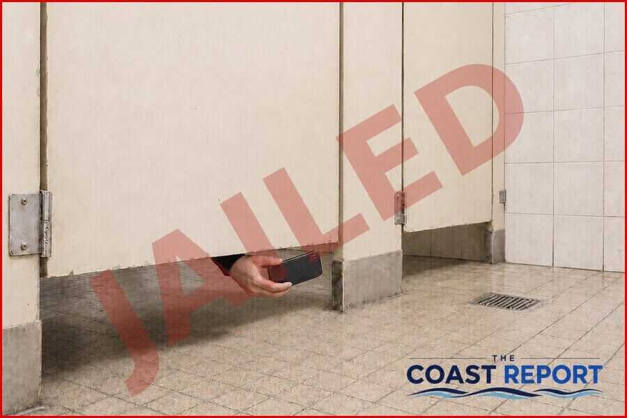 Man holding a mobile phone beneath a public-toilet cubicle divider with a transparent JAILED overlay